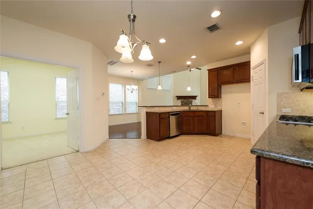a large kitchen with a large counter top a sink stainless steel appliances and cabinets