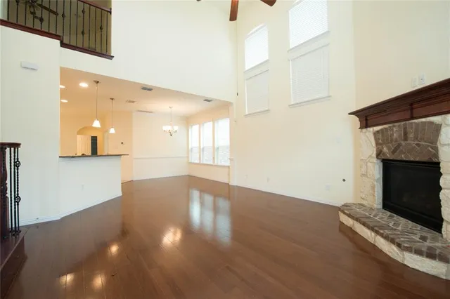 a view of an empty room with wooden floor and a fireplace
