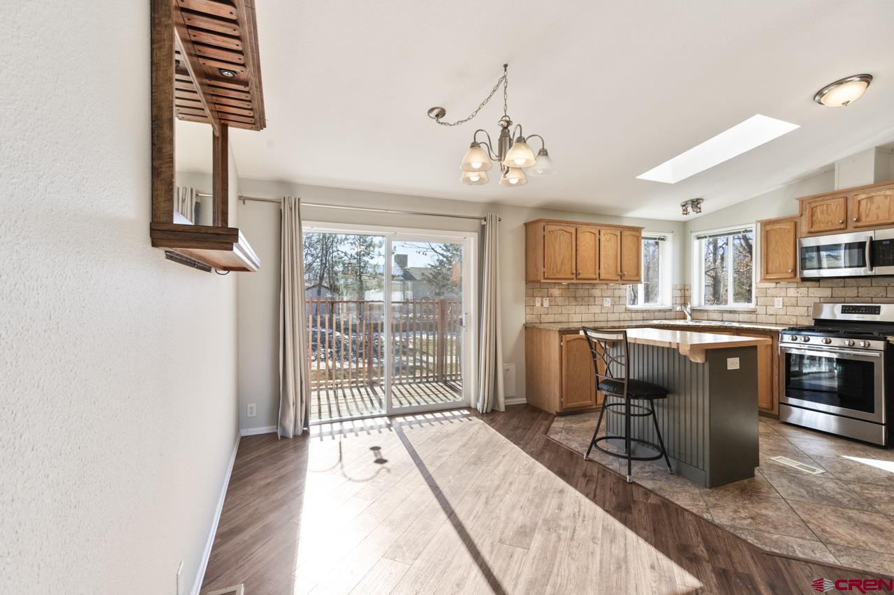 901 6530 Road, Unit 1312 Montrose, CO 81401 - Photo 26 of 30 a kitchen with stainless steel appliances kitchen island granite countertop a refrigerator a stove a sink dishwasher and white cabinets with wooden floor
