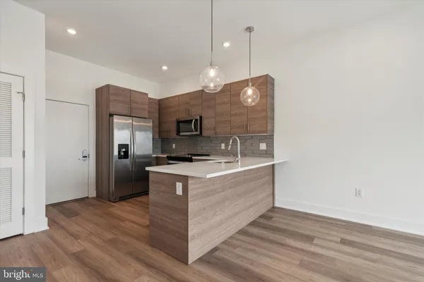 a kitchen with stainless steel appliances granite countertop a sink a stove and a wooden floor