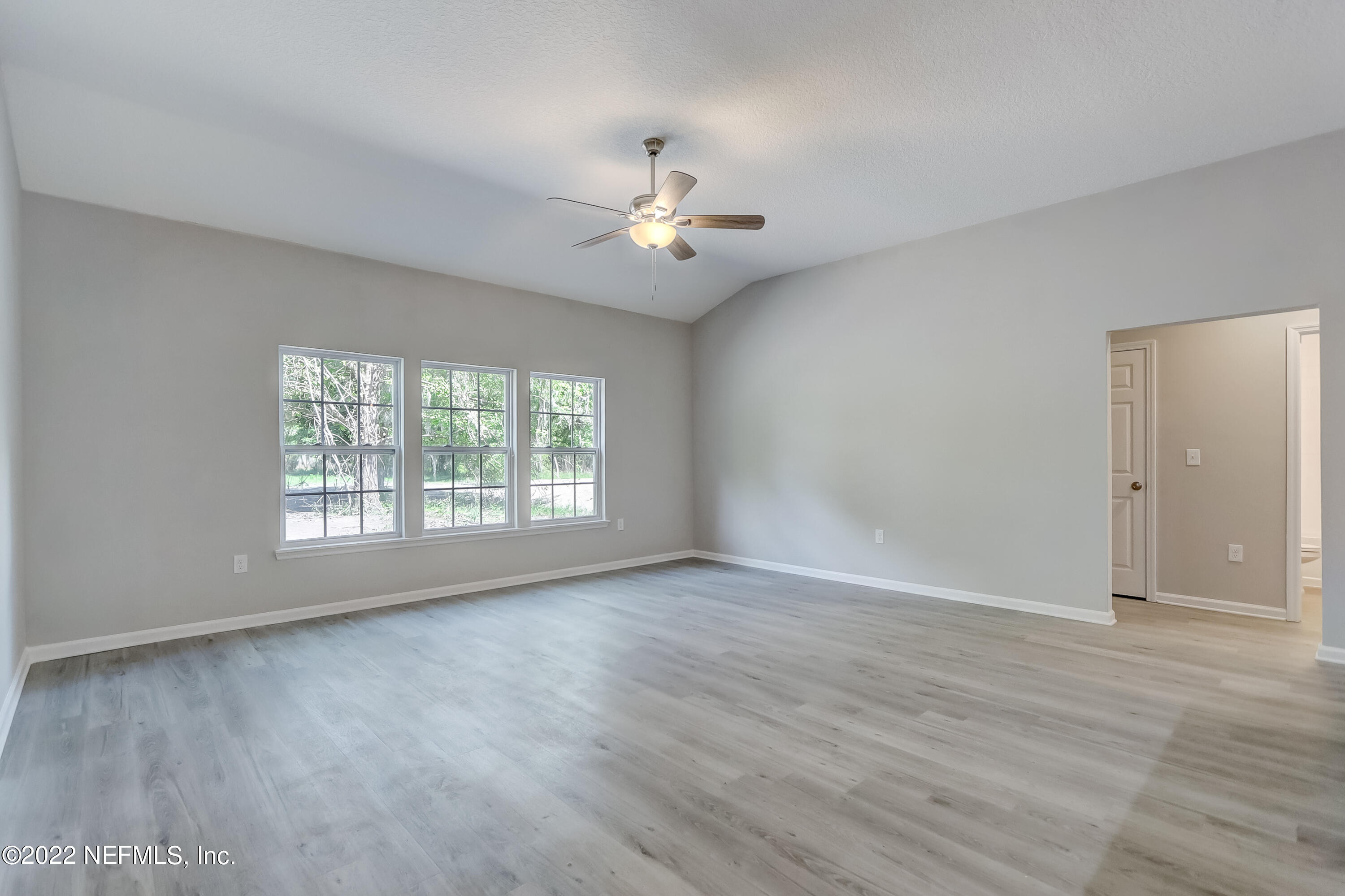 1187 Hatcher Road Middleburg, FL 32068 - Photo 23 of 42 an empty room with wooden floor chandelier fan and windows