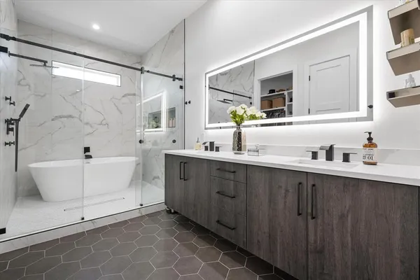 a bathroom with a double vanity sink mirror and bathtub