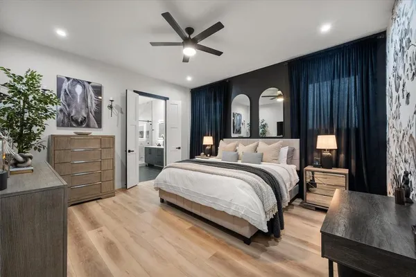a spacious bedroom with a bed a dresser and paintings on the wall