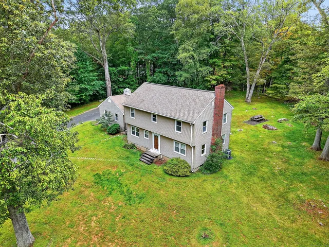 an aerial view of a house with yard and large trees