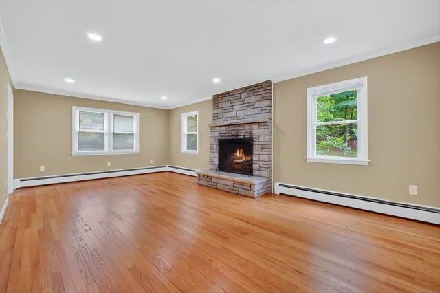 an empty room with wooden floor fireplace and windows