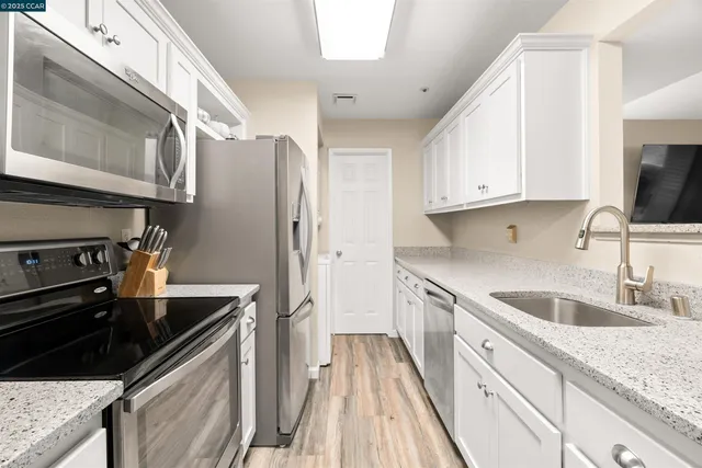a kitchen with granite countertop a sink stove and refrigerator