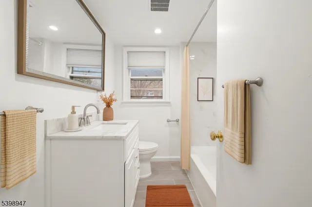 a bathroom with a granite countertop sink a toilet a shower and a mirror