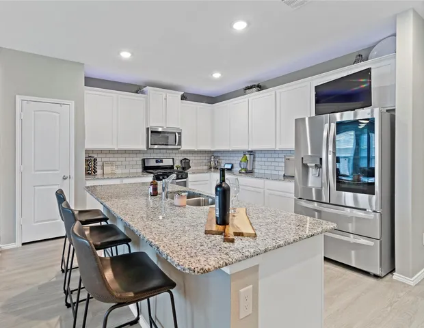 a kitchen with stainless steel appliances granite countertop a stove a sink and white cabinets