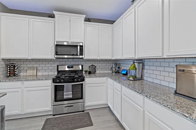 a large white kitchen with sink stove and cabinets