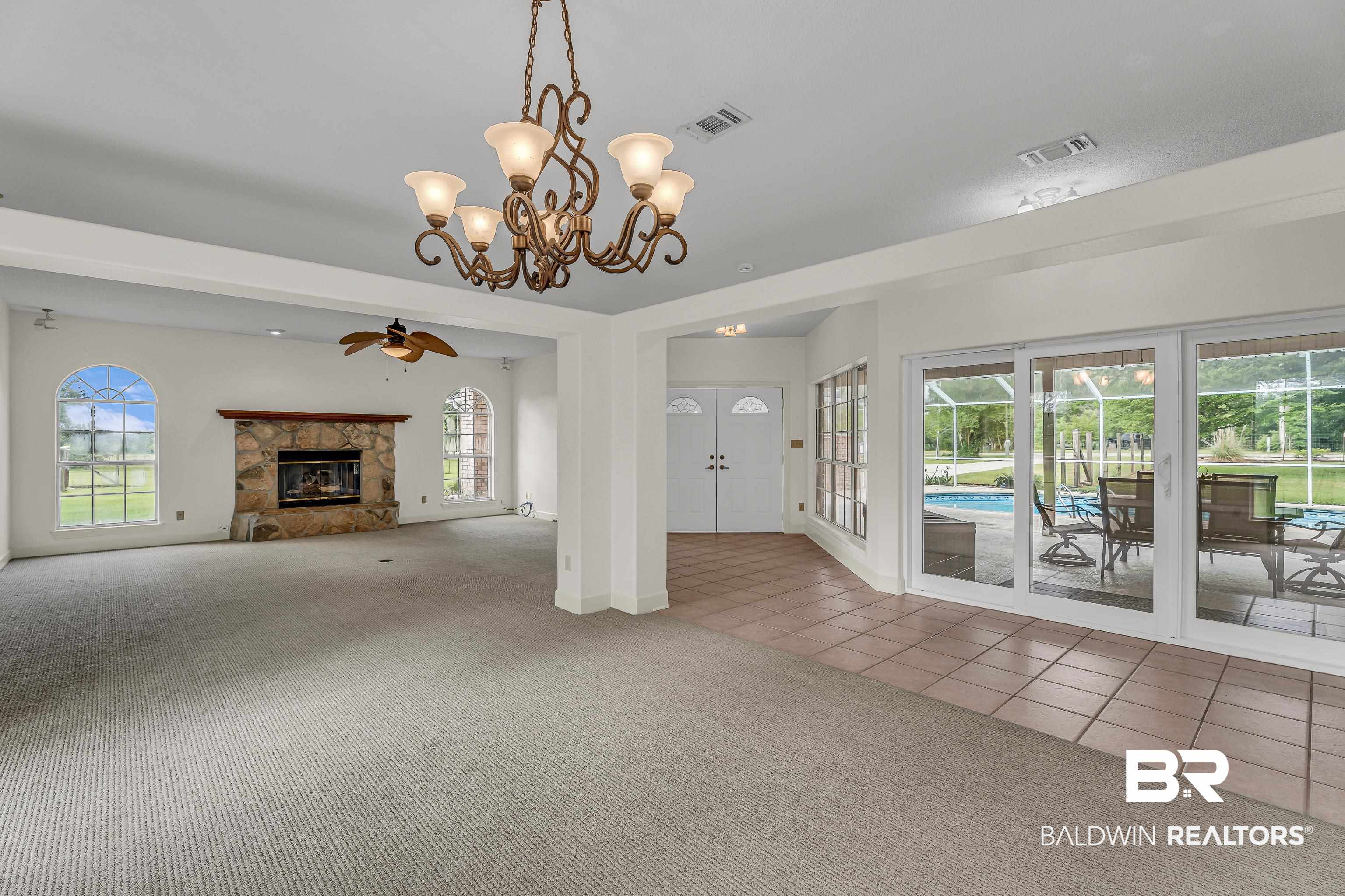 9530 Pilgrim Drive Elberta, AL 36530 - Photo 4 of 61 Unfurnished living room with a glass covered fireplace, carpet flooring, ceiling fan with notable chandelier, and visible vents