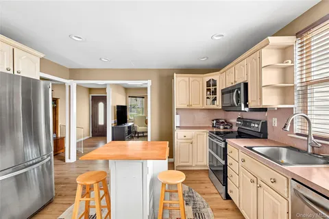 a kitchen with stainless steel appliances granite countertop a sink a stove top oven a refrigerator cabinets and a dining table