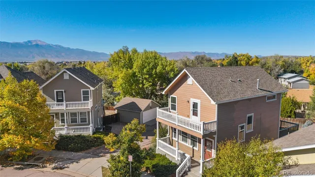 a view of a white house next to a yard with large trees