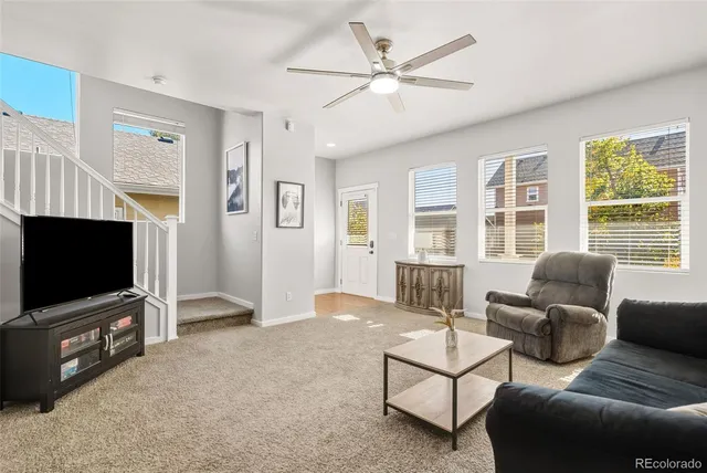 a living room with furniture a flat screen tv and large window