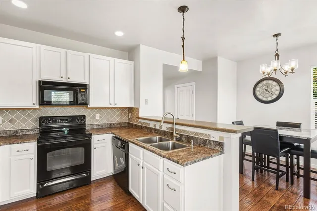 a kitchen with granite countertop a sink a stove a oven a dining table and chairs