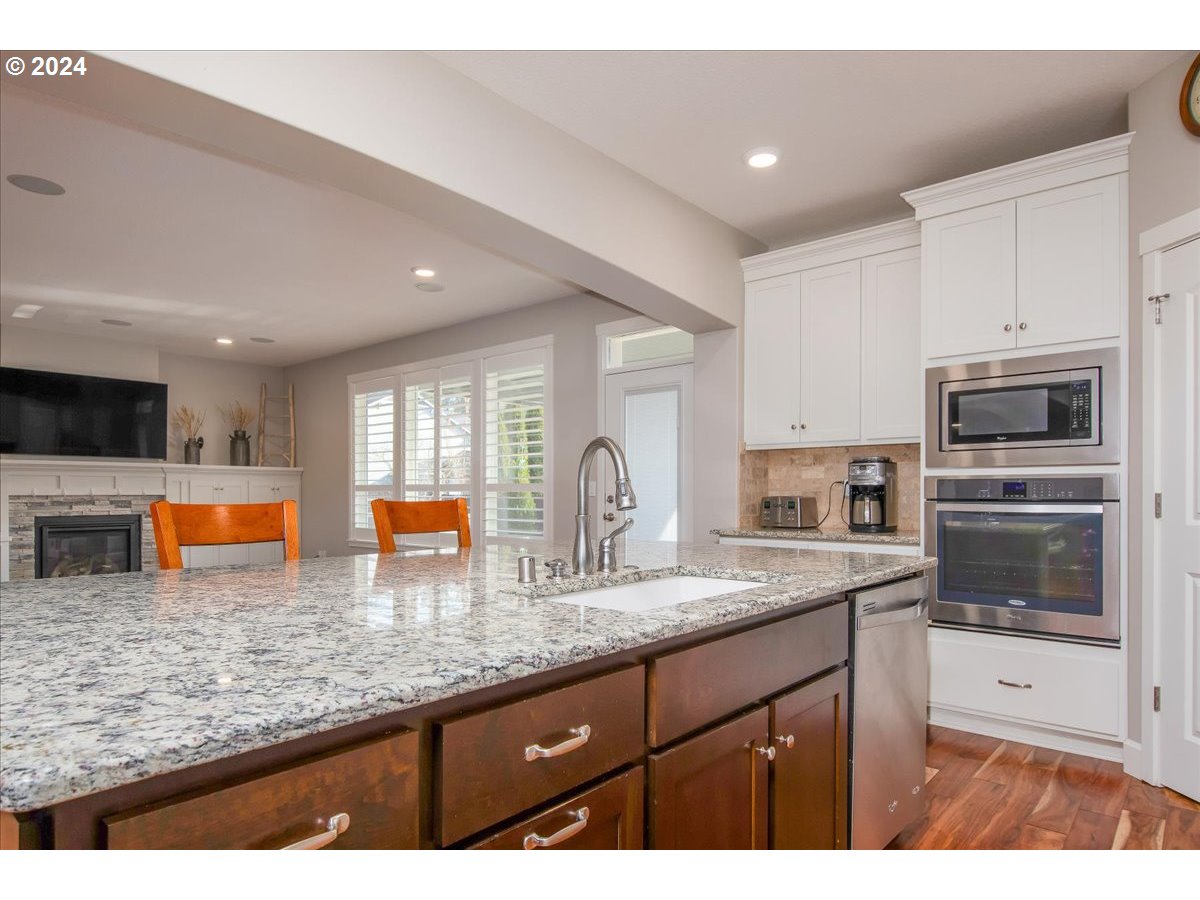 756 North 47th Avenue Ridgefield, WA 98642 - Photo 14 of 42 a kitchen with stainless steel appliances granite countertop a stove a sink a microwave a refrigerator and white cabinets with wooden floor