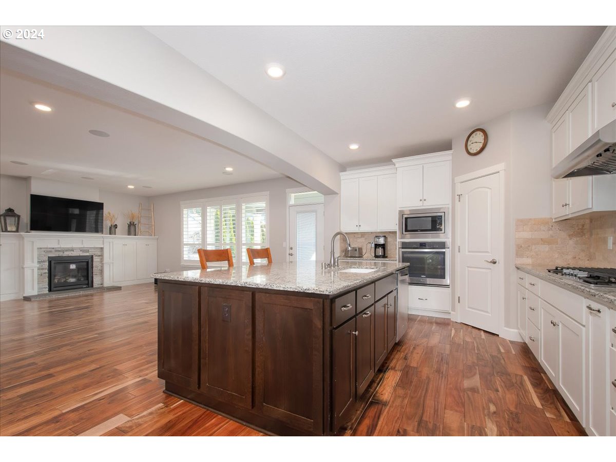 756 North 47th Avenue Ridgefield, WA 98642 - Photo 8 of 42 a kitchen with stainless steel appliances granite countertop a stove top oven a sink dishwasher and a refrigerator with wooden floor