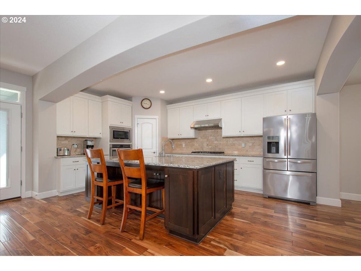 756 North 47th Avenue Ridgefield, WA 98642 - Photo 9 of 42 a kitchen with stainless steel appliances kitchen island granite countertop a table chairs and a refrigerator