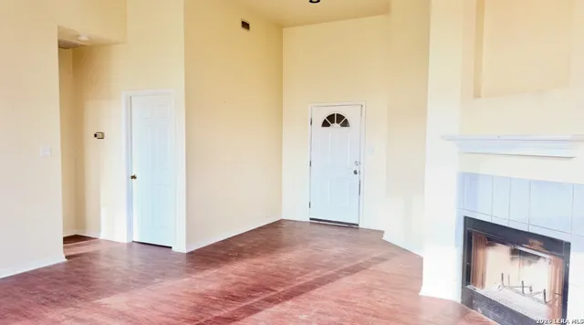 a view of an empty room with wooden floor and a fireplace