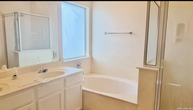 a bathroom with a tub sink vanity and mirror