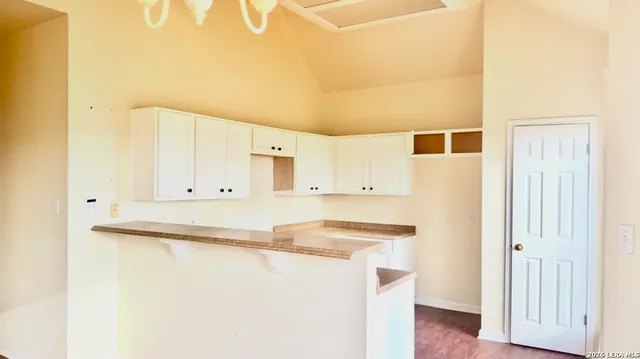 a kitchen with stainless steel appliances granite countertop a refrigerator a stove and white cabinets with wooden floor