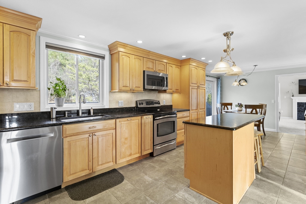 66 Clover Hill Circle Tyngsborough, MA 01879 - Photo 3 of 42 a kitchen with stainless steel appliances granite countertop a stove top oven a sink a dining table and chairs