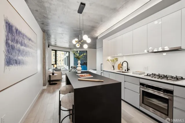 a kitchen with stainless steel appliances granite countertop a sink dishwasher a stove and white cabinets with wooden floor