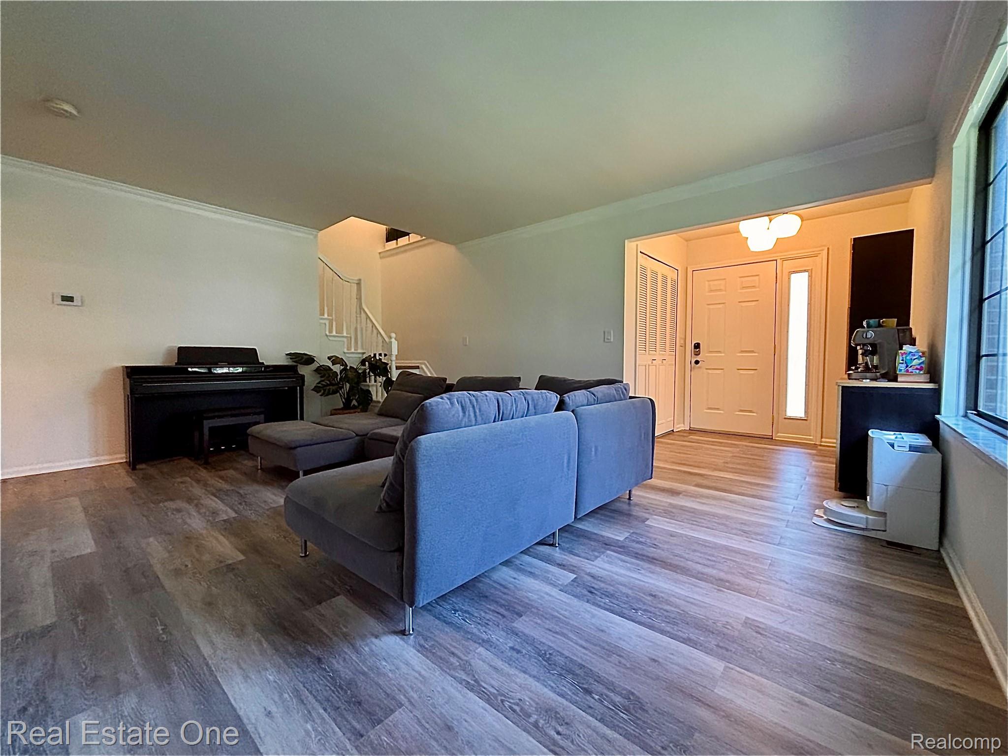 66 Meadow Wood Drive Rochester, MI 48307 - Photo 3 of 20 Open-concept living space with wood-finish flooring, crown molding, and a prominent staircase