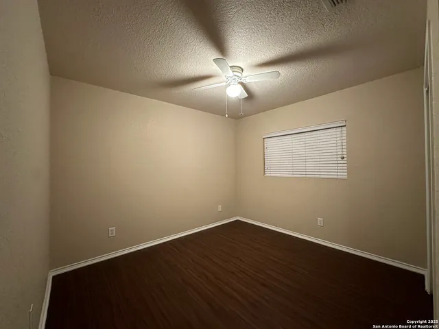 a view of a room with wooden floor and a ceiling fan