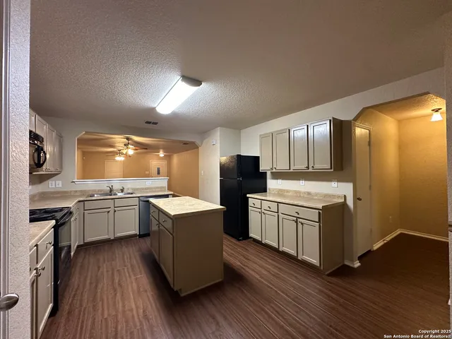 a kitchen with cabinets wooden floor and stainless steel appliances