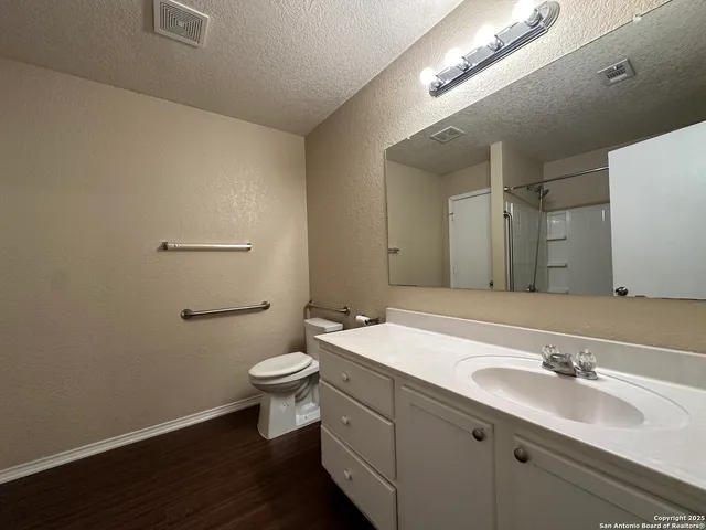 a bathroom with a granite countertop sink a toilet and a mirror
