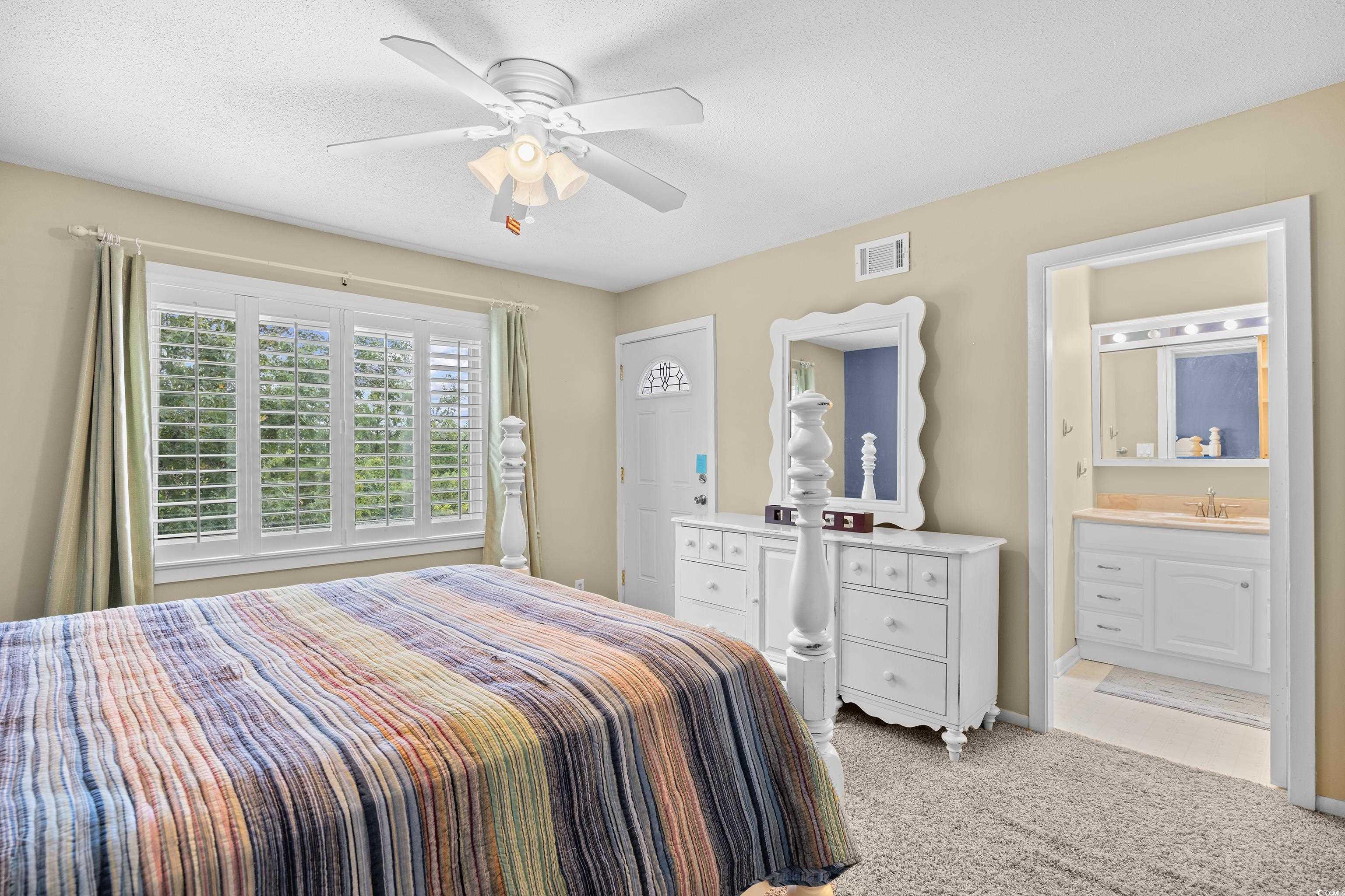 500 Eagle Way, Unit 4 Little River, SC 29566 - Photo 8 of 19 Bedroom with light colored carpet, a textured ceiling, ensuite bathroom, and a ceiling fan
