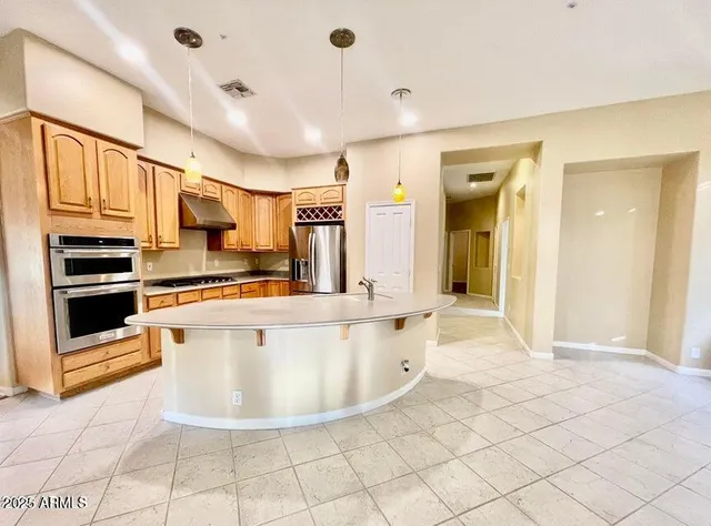 a view of kitchen with stainless steel appliances kitchen island granite countertop a sink and cabinets