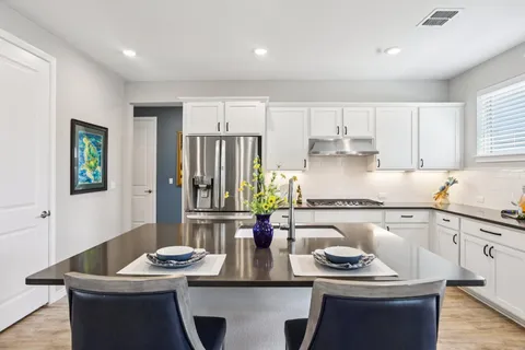 a living room with furniture kitchen view and a large window