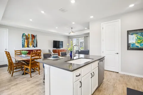 a kitchen with stainless steel appliances granite countertop a sink a stove a refrigerator and white cabinets with wooden floor