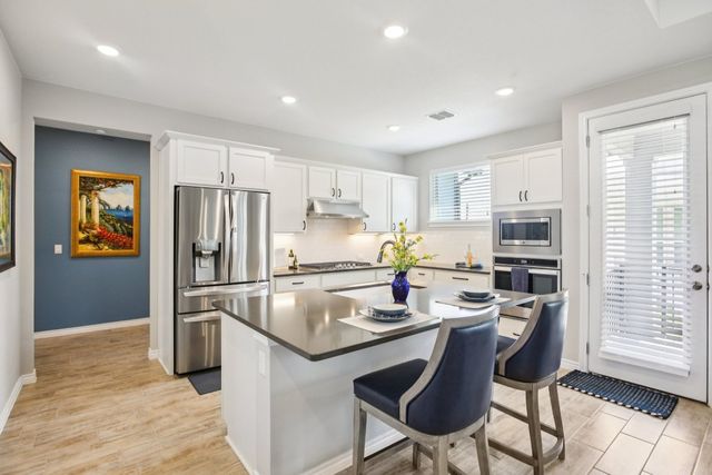 a kitchen with stainless steel appliances granite countertop a refrigerator a stove microwave and a refrigerator