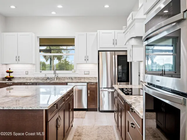 a kitchen with stainless steel appliances granite countertop a refrigerator a stove and a sink