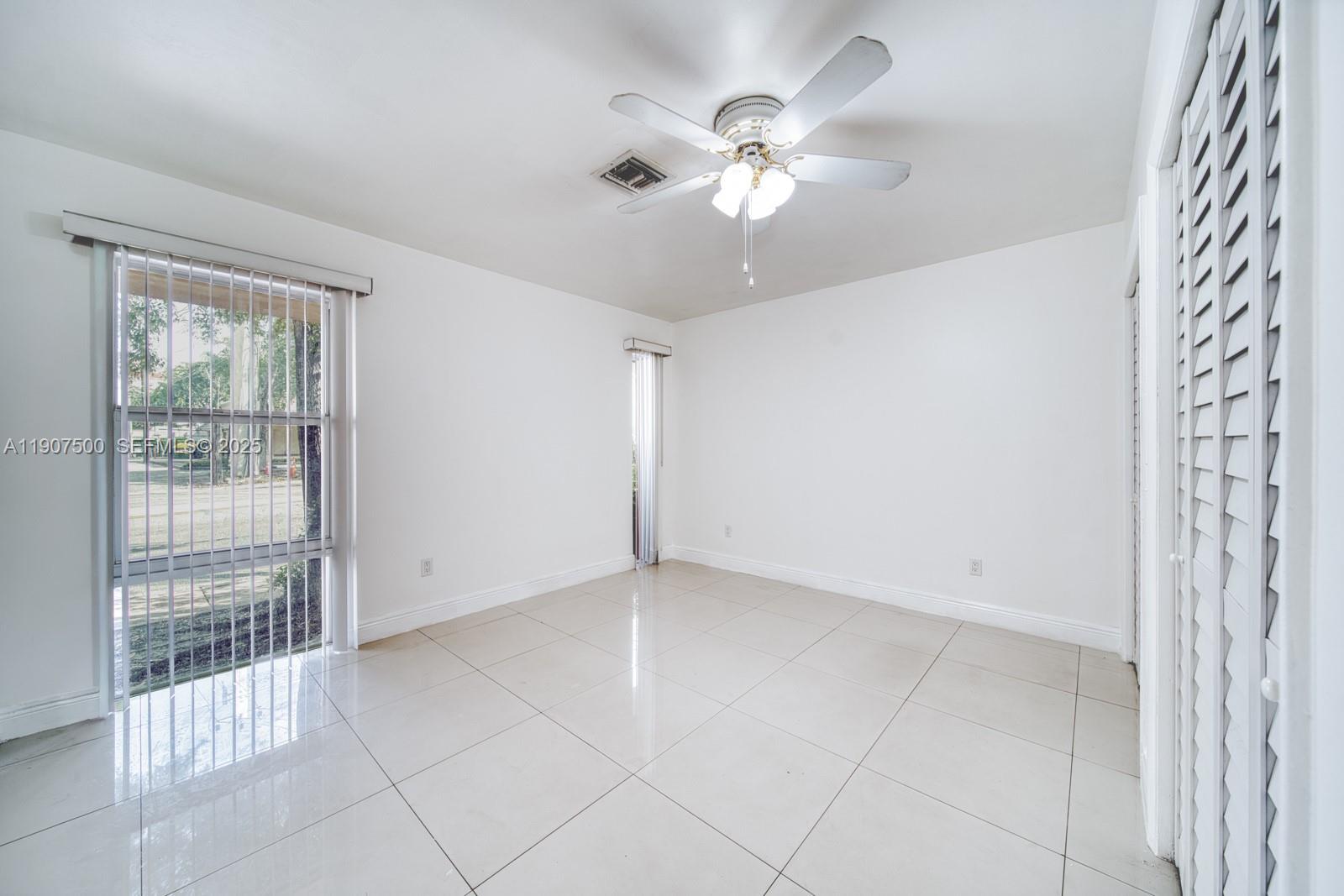 400 Minorca Avenue, Unit 1 Coral Gables, FL 33134 - Photo 13 of 21 an empty room with chandelier fan and windows