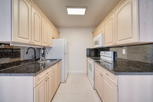 a kitchen with granite countertop a sink stainless steel appliances and cabinets