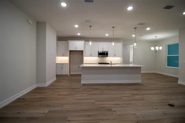 a view of kitchen with kitchen island microwave and wooden floor