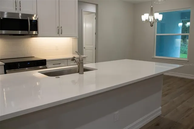 a kitchen with stainless steel appliances a sink a stove a microwave and cabinets