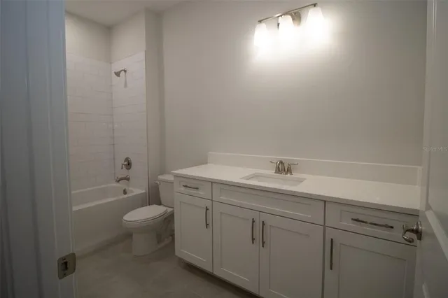 a bathroom with a granite countertop sink a toilet and shower