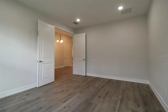a view of an empty room with wooden floor and closet