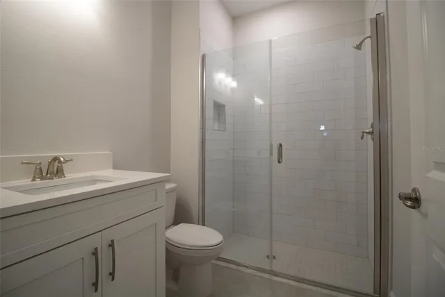 a bathroom with a granite countertop sink a toilet and shower