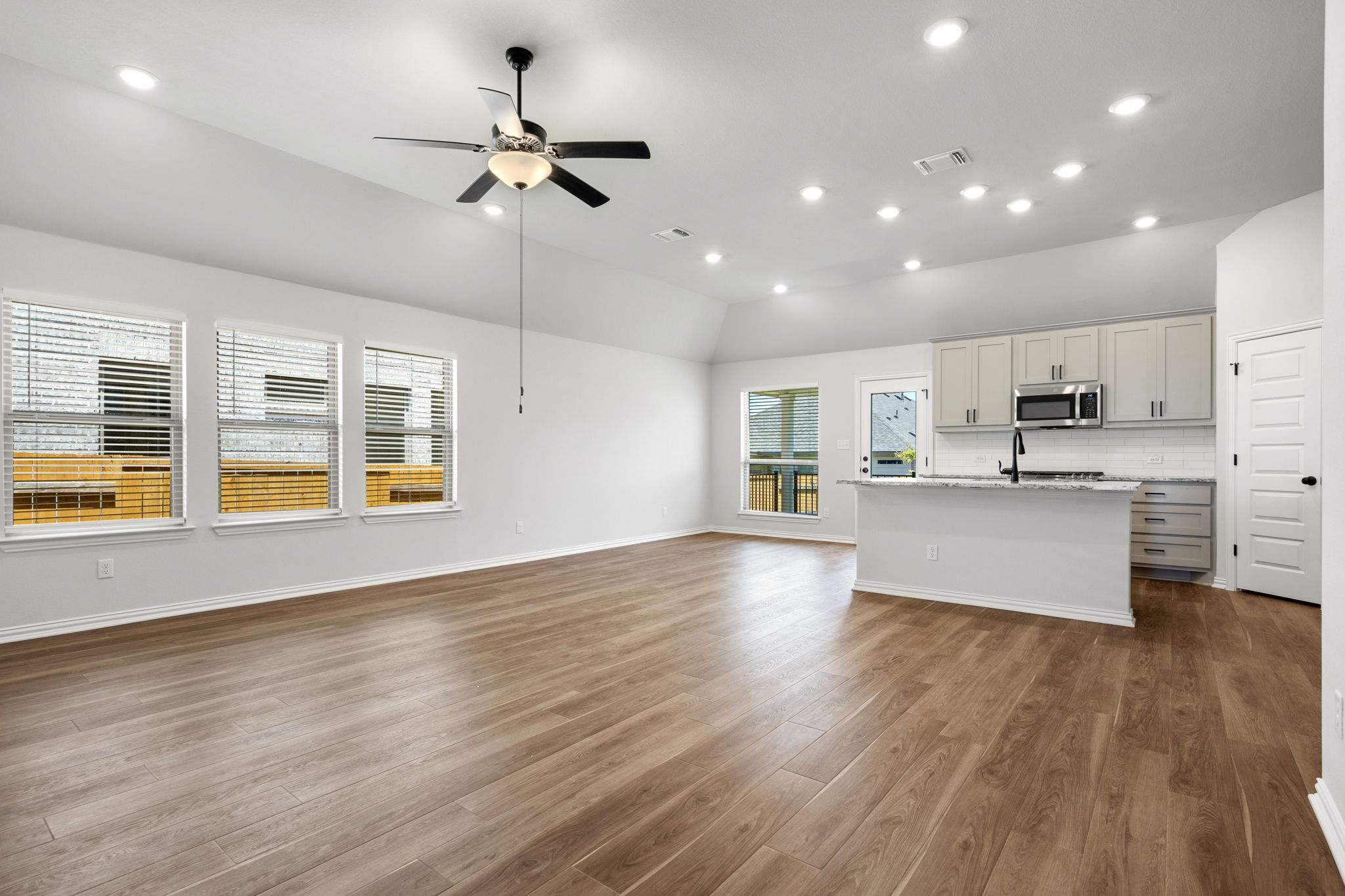 341 Fawn Riv Run Kyle, TX 78640 - Photo 27 of 29 Kitchen with visible vents, a kitchen island with sink, stainless steel microwave, lofted ceiling, and open floor plan