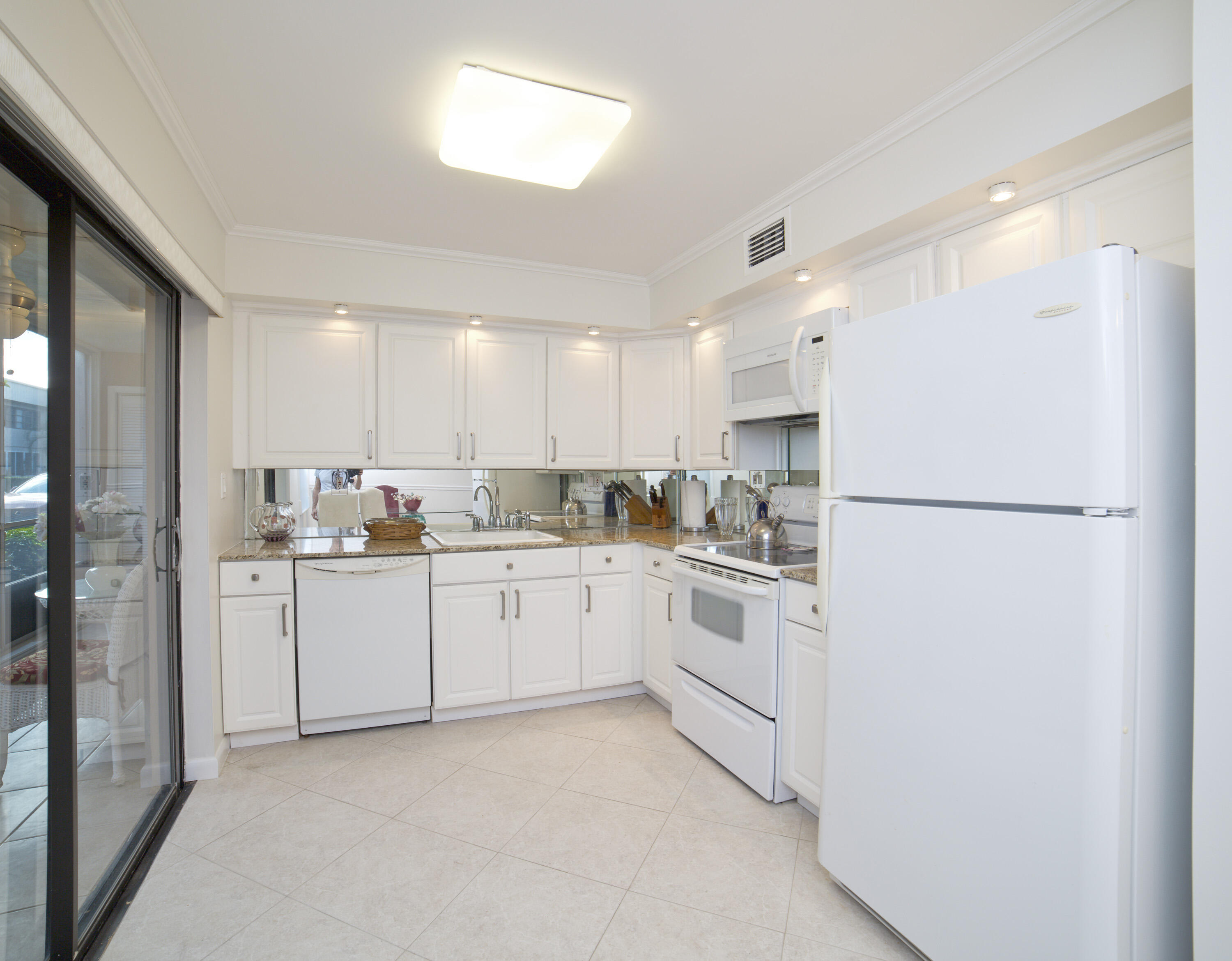 247 Capri F Delray Beach, FL 33484 - Photo 1 of 30 a kitchen with white cabinets and white appliances