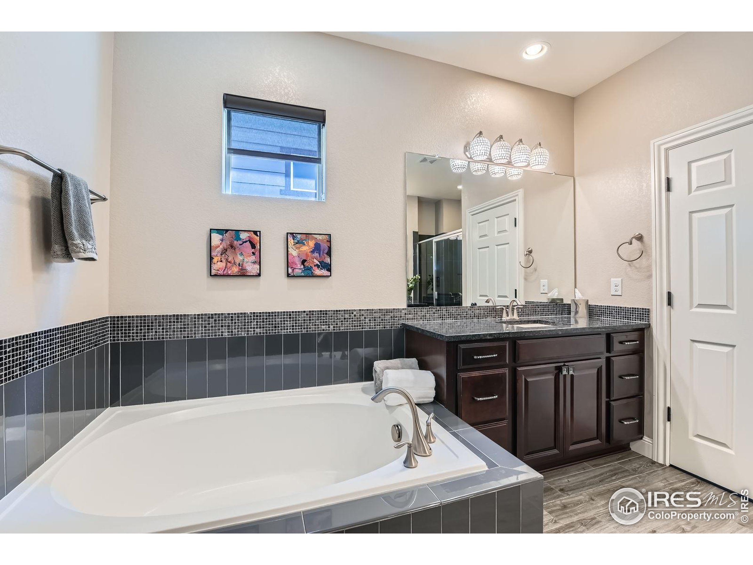10834 Graphite Street Broomfield, CO 80021 - Photo 17 of 34 a bathroom with a tub a double vanity sink and a large mirror
