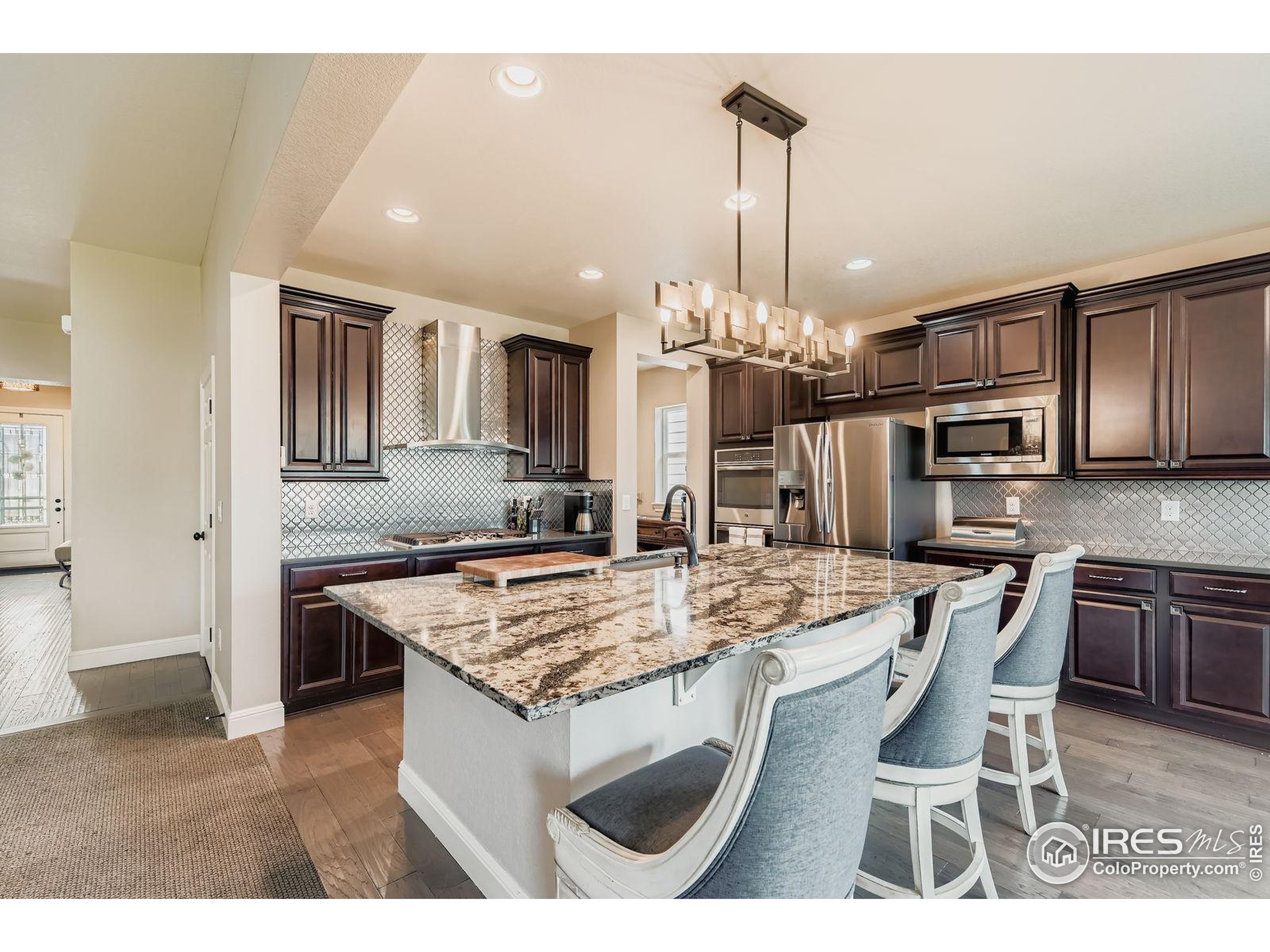 10834 Graphite Street Broomfield, CO 80021 - Photo 5 of 34 a kitchen with kitchen island granite countertop stainless steel appliances a sink stove and refrigerator