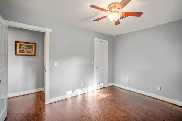 an empty room with wooden floor and a ceiling fan