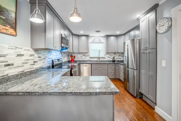 a kitchen with stainless steel appliances granite countertop a sink a stove and a refrigerator
