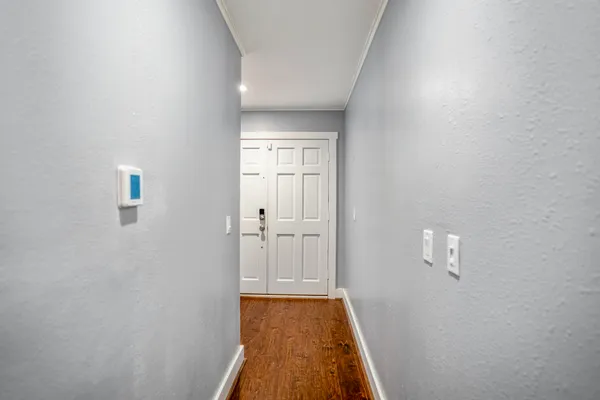 a view of a hallway with wooden floor and a bathroom